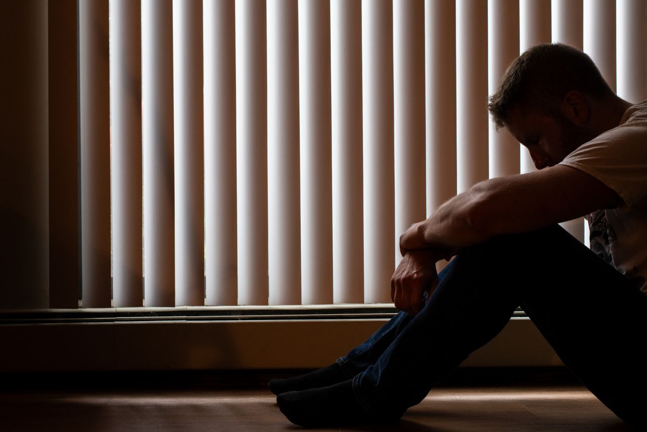Person sitting alone in a dimly lit room representing the weight of depression - Every Day Counts Person sitting alone in a dimly lit room representing the weight of depression
